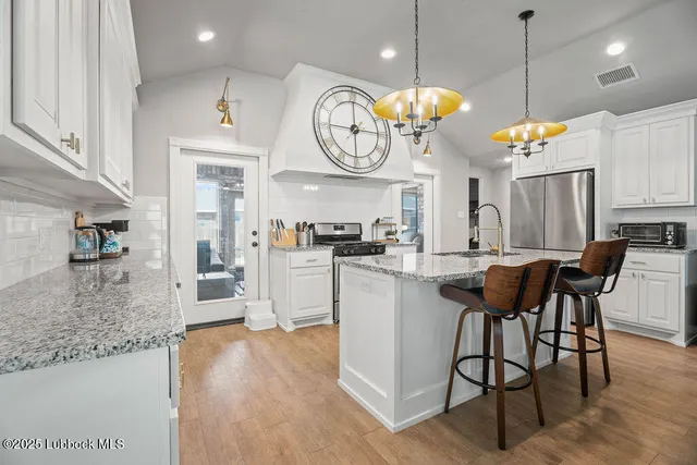 a kitchen with stainless steel appliances granite countertop a stove a refrigerator a microwave oven with a dining table and chairs