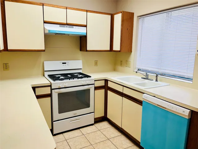 a kitchen with granite countertop a sink a stove and cabinets