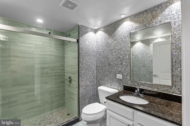 a bathroom with a granite countertop sink a toilet and shower
