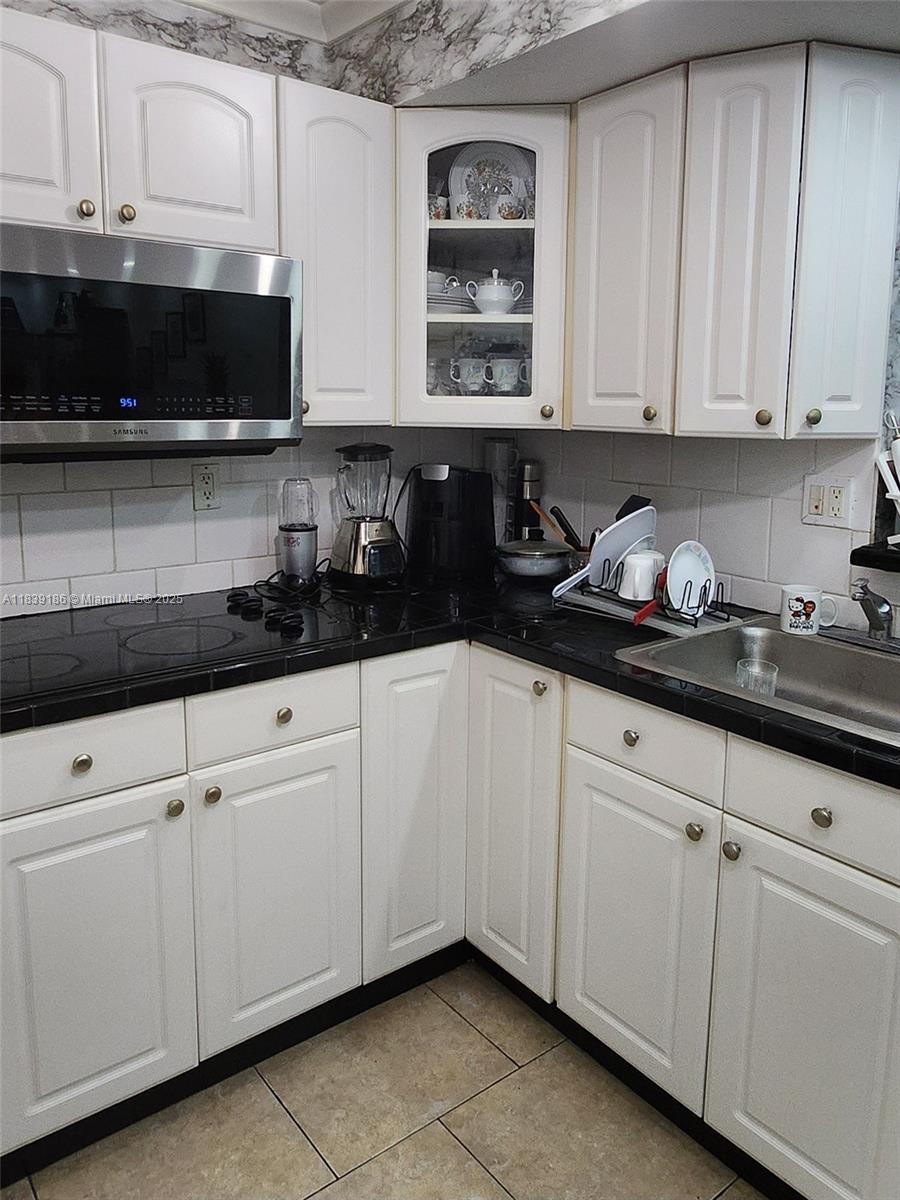 2750 Northeast 183rd Street, Unit 1701 Aventura, FL 33160 - Photo 13 of 40 a kitchen with granite countertop white cabinets and sink