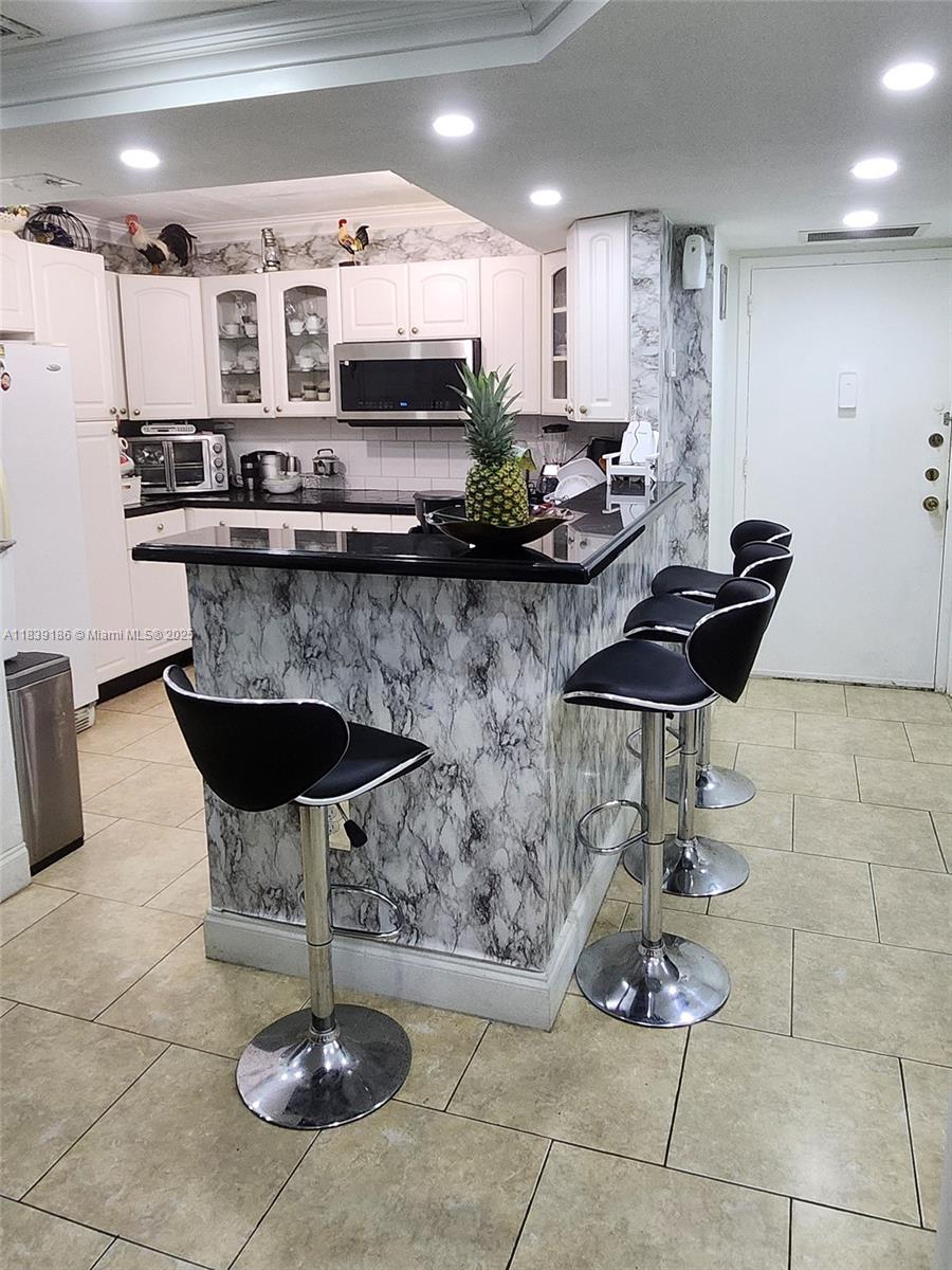2750 Northeast 183rd Street, Unit 1701 Aventura, FL 33160 - Photo 9 of 40 a kitchen with stainless steel appliances kitchen island granite countertop a table and chairs in it