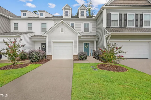 a view of a white house next to a yard and a large tree