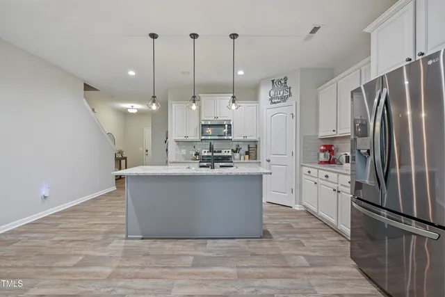 a large kitchen with stainless steel appliances kitchen island granite countertop a refrigerator a oven a kitchen island with wooden floor