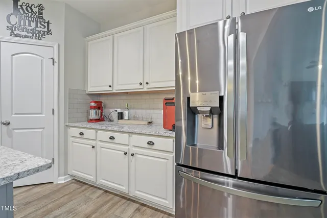 a kitchen with stainless steel appliances granite countertop a refrigerator and white cabinets