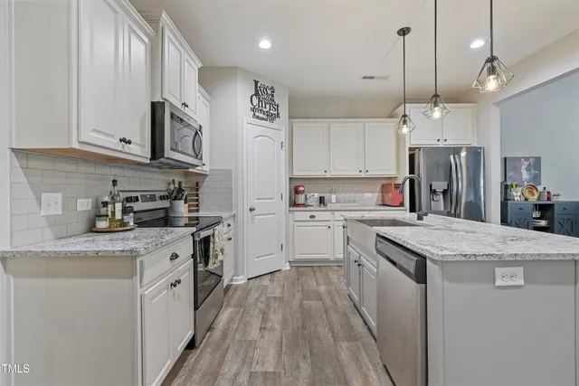 a kitchen with granite countertop a sink cabinets stainless steel appliances and a counter top space