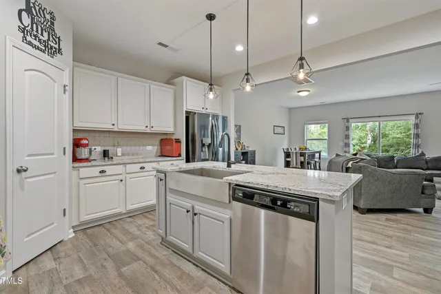 a kitchen with kitchen island granite countertop a stove a sink a dining table and chairs with wooden floor