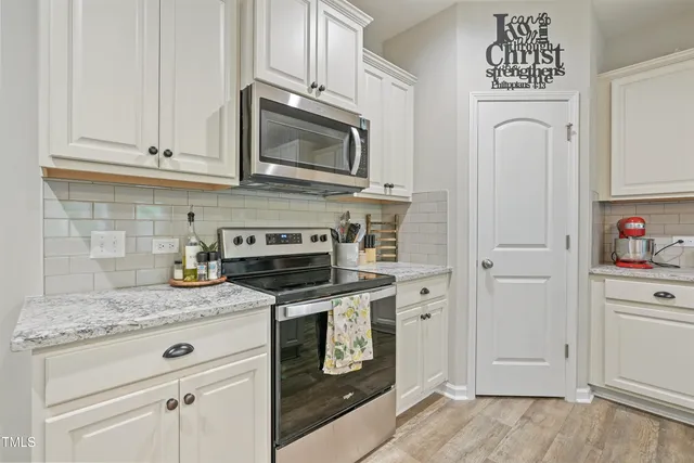 a kitchen with granite countertop white cabinets and stainless steel appliances