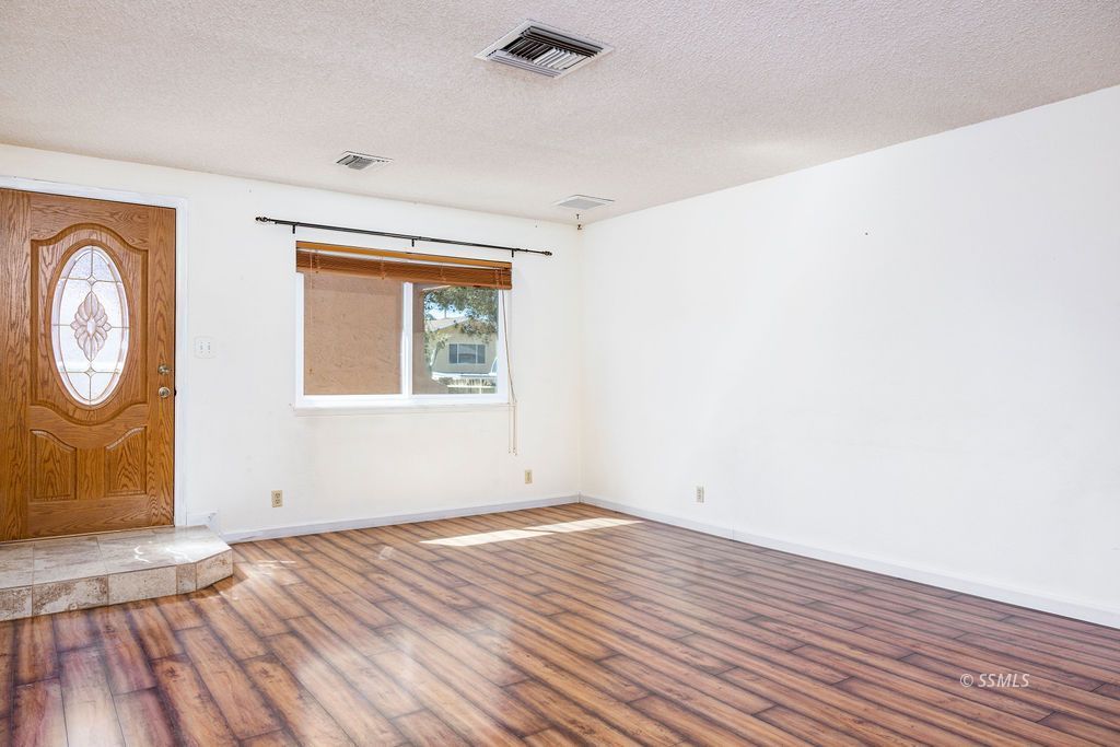 1144 West Benson Avenue Ridgecrest, CA 93555 - Photo 8 of 32 an empty room with wooden floor and windows