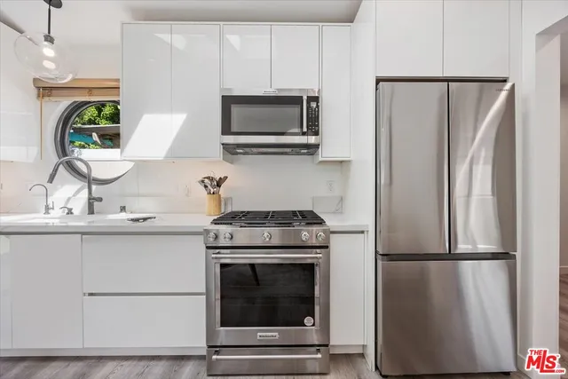 a living room with furniture a large window and stainless steel appliances