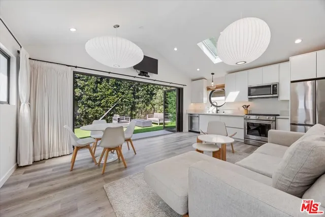 a living room with furniture a large window and stainless steel appliances