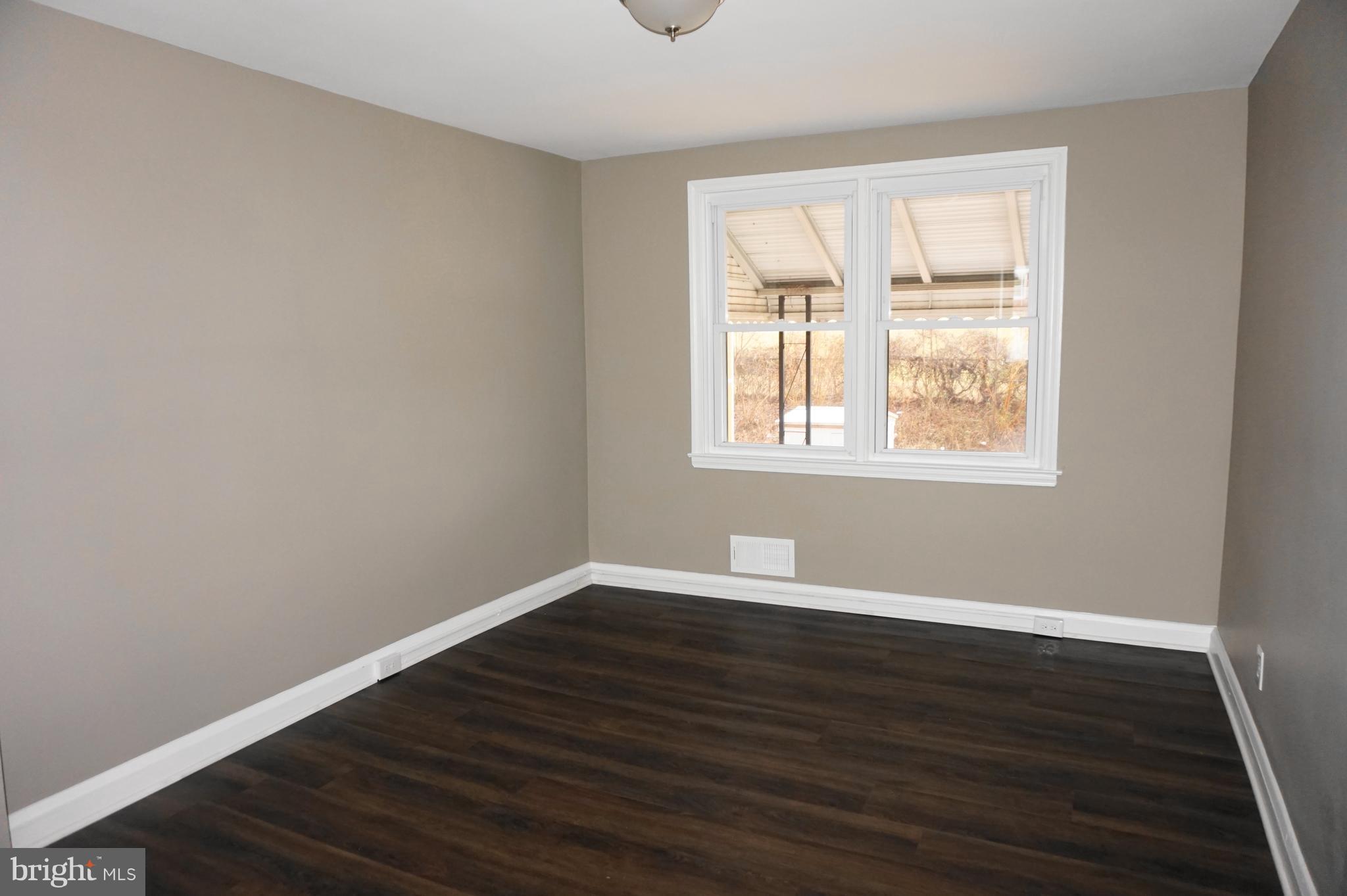 7459 School Avenue Dundalk, MD 21222 - Photo 6 of 23 a view of an empty room with wooden floor and a window