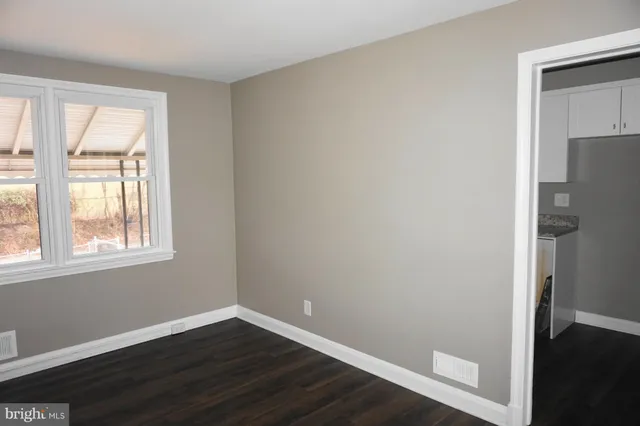 an empty room with wooden floor and a window