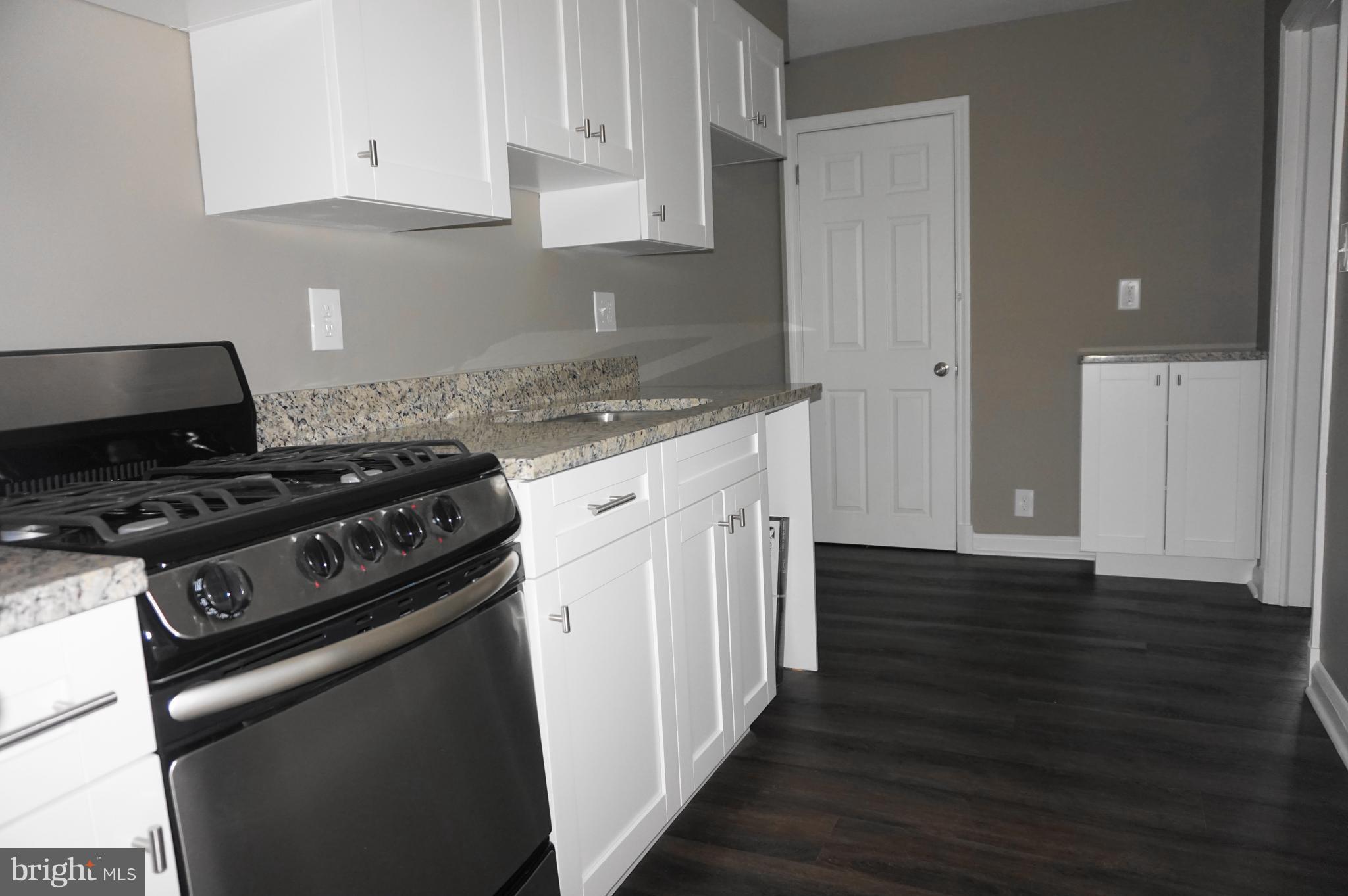 7459 School Avenue Dundalk, MD 21222 - Photo 8 of 23 a kitchen with wooden floor and a stove top oven
