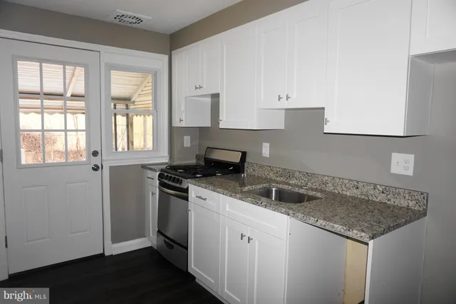 a kitchen with granite countertop a sink and a stove