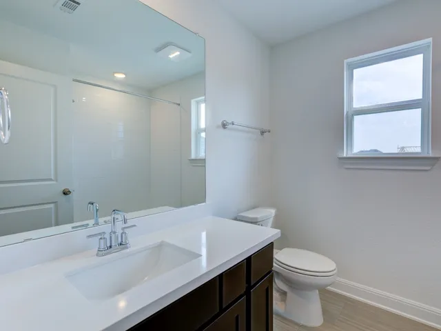 a bathroom with a sink a toilet and a window