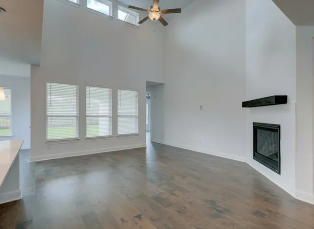 an empty room with wooden floor fireplace and windows