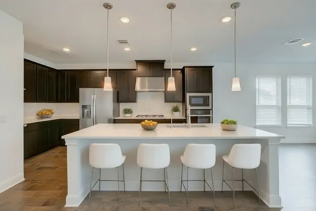 a kitchen with granite countertop a counter space chairs stainless steel appliances and cabinets