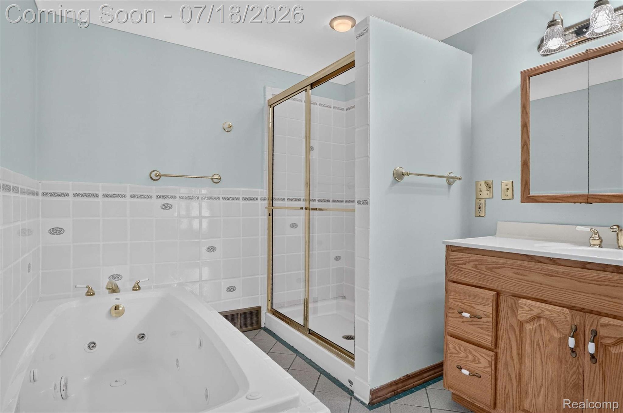 1437 East Cook Road Grand Blanc, MI 48439 - Photo 57 of 69 Corner jetted soaking tub, separate glass-enclosed shower, wood-finish vanity with an integrated sink, and a mirrored medicine cabinet