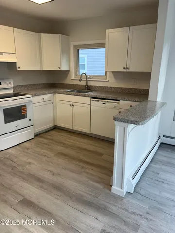 a white kitchen with granite countertop a sink and cabinets