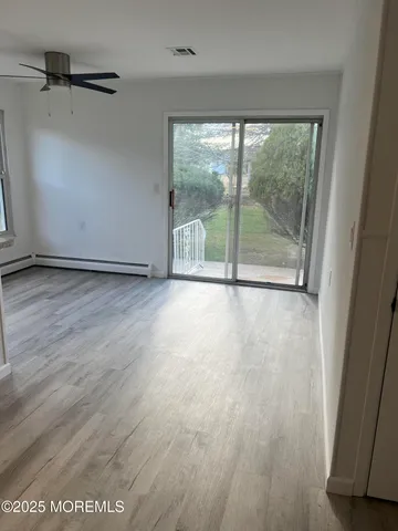 a view of an empty room with wooden floor and a window