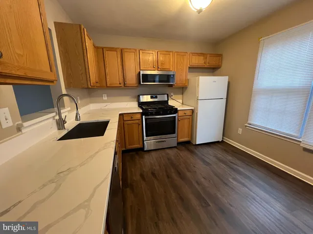 a kitchen with granite countertop wooden floors a stove and a refrigerator