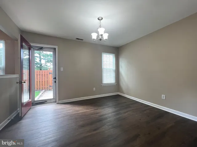 an empty room with wooden floor chandelier and windows