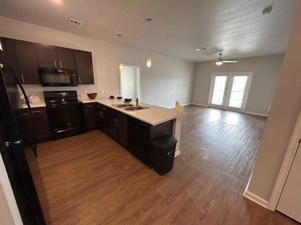 a kitchen with kitchen island granite countertop a sink dishwasher stove and wooden cabinets
