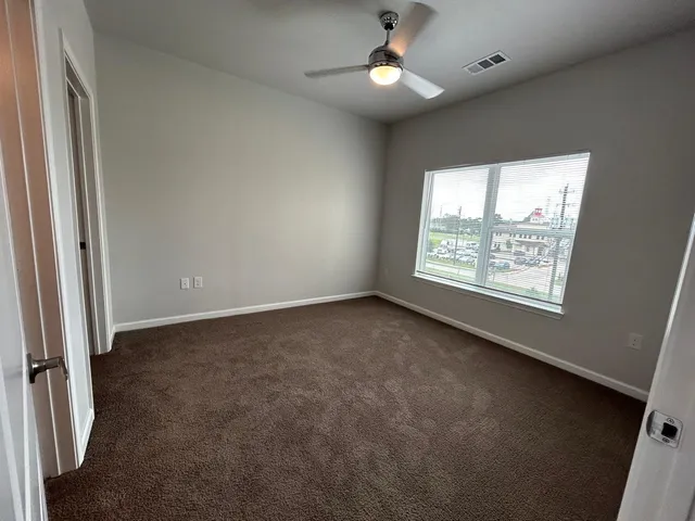en empty room with windows and ceiling fan