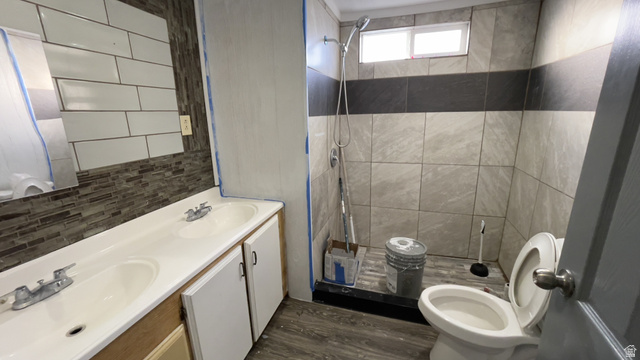 2491 Highway 89, Unit 114 Pleasant View, UT 84404 - Photo 6 of 18 Full bathroom featuring a stall shower, double vanity, backsplash, and dark wood-style flooring