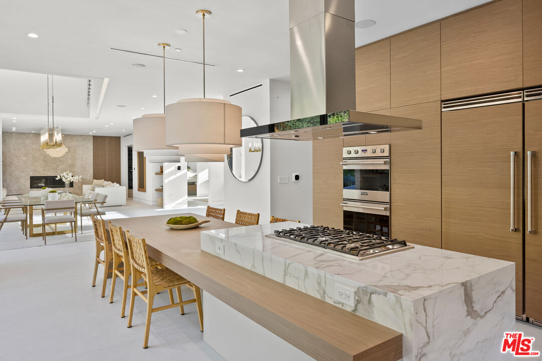 2814 Roscomare Road Los Angeles, CA 90077 - Photo 14 of 35 a kitchen with stainless steel appliances kitchen island granite countertop a stove a refrigerator a oven a sink a dining table and chairs