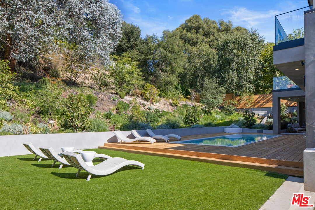 2814 Roscomare Road Los Angeles, CA 90077 - Photo 28 of 35 a view of a swimming pool with lawn chairs and plants