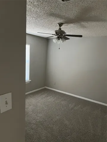 an empty room with a ceiling fan and a window