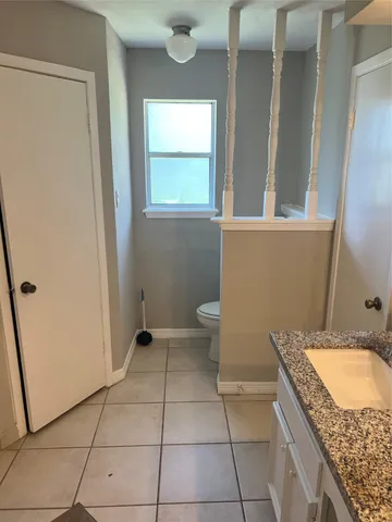 a bathroom with a granite countertop sink a toilet and a mirror