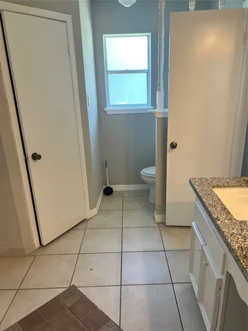 a bathroom with a granite countertop sink a toilet and a mirror