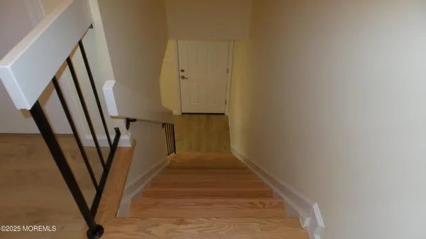 a view of a hallway with wooden floor and stairs