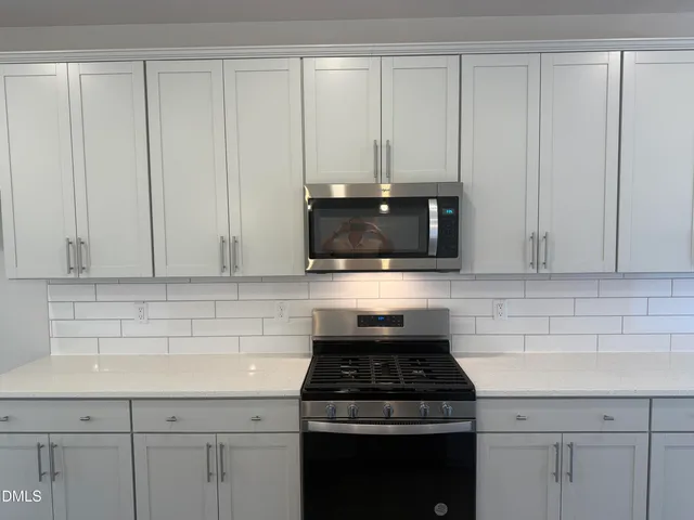 a kitchen with granite countertop white cabinets and stainless steel appliances