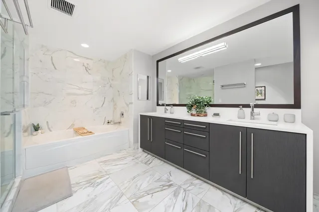 a bathroom with a bathtub sink double vanity mirror and a shower