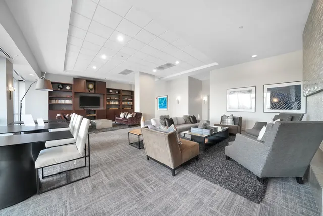 a large hall with stainless steel appliances granite countertop a barbecue grill and couches with wooden floor