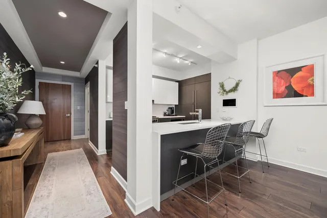 a kitchen with stainless steel appliances kitchen island granite countertop dining table chairs and a refrigerator