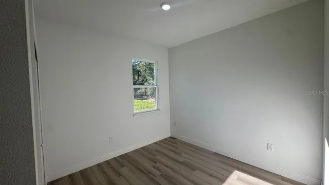 a view of an empty room with window and wooden floor