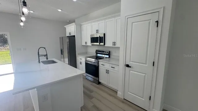 a kitchen with stainless steel appliances a refrigerator sink and white cabinets