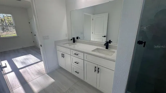 a bathroom with a double vanity sink and mirror with window