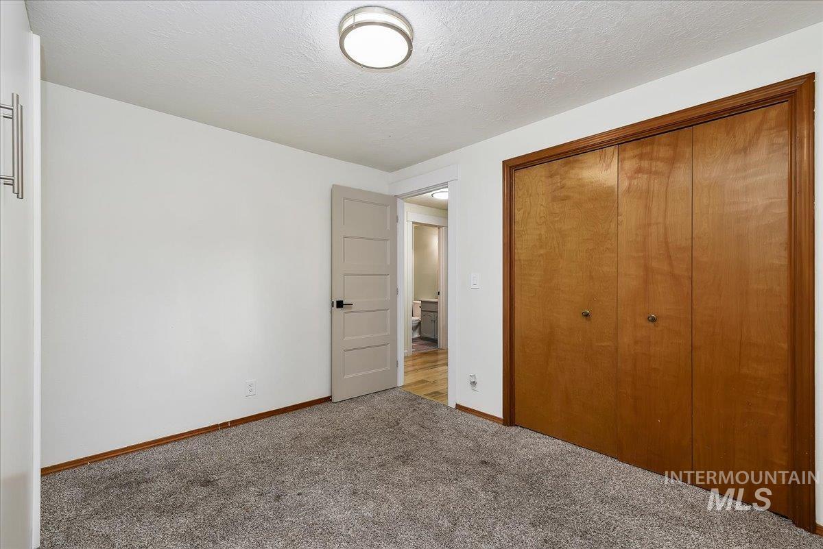 9215 West Preece Street Boise, ID 83704 - Photo 12 of 22 Bedroom featuring neutral grey carpet, white walls, and a warm wood-toned closet with double doors