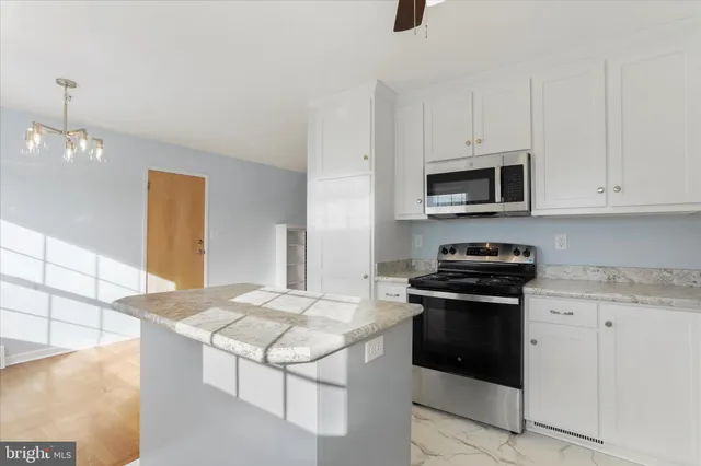 a kitchen with kitchen island granite countertop a stove top oven a sink a counter space and cabinets