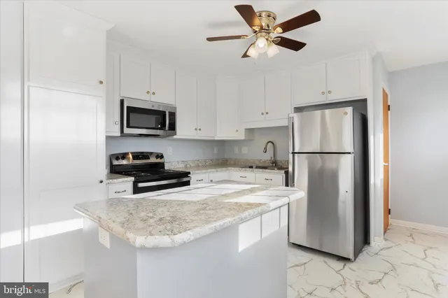 a kitchen with stainless steel appliances granite countertop a refrigerator a stove a sink and white cabinets