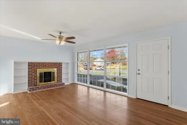 an empty room with wooden floor fireplace and windows