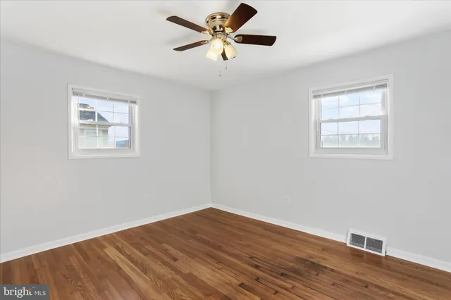 a view of an empty room with window and wooden floor