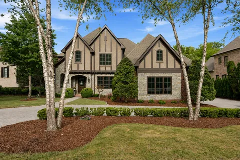 a front view of a house with a yard and trees