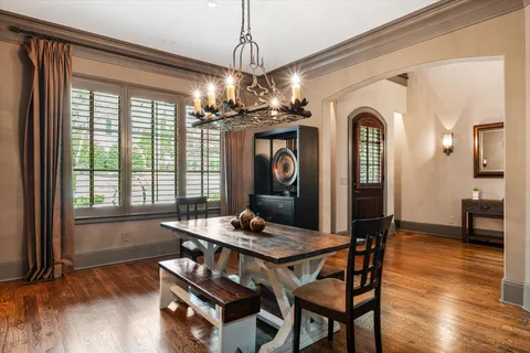 a dining room with wooden floor a chandelier a wooden table and chairs