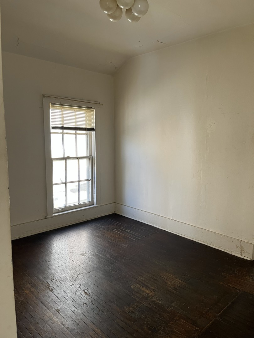 518 Hamilton Street Evanston, IL 60202 - Photo 9 of 15 an empty room with wooden floor and windows with curtains